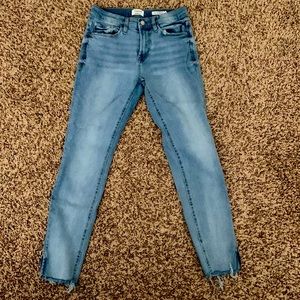 Light wash blue jeans with destress on the back and front pockets and ankle seam